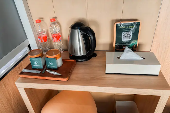 Air mineral, teh, gelas, dan teko listrik sudah disediakan