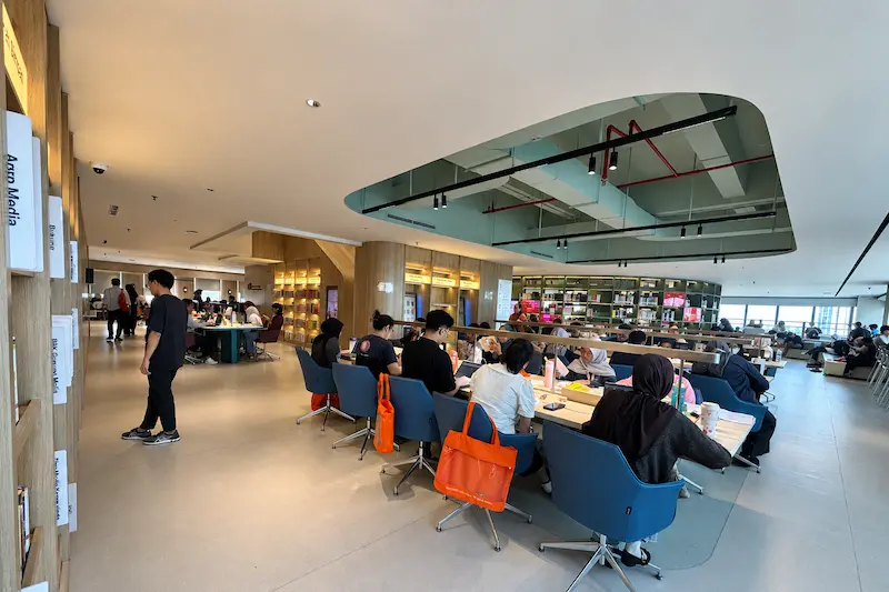 Salah satu area baca di perpustakaan yang dilengkapi meja dan stop kontak untuk charge ponsel atau laptop